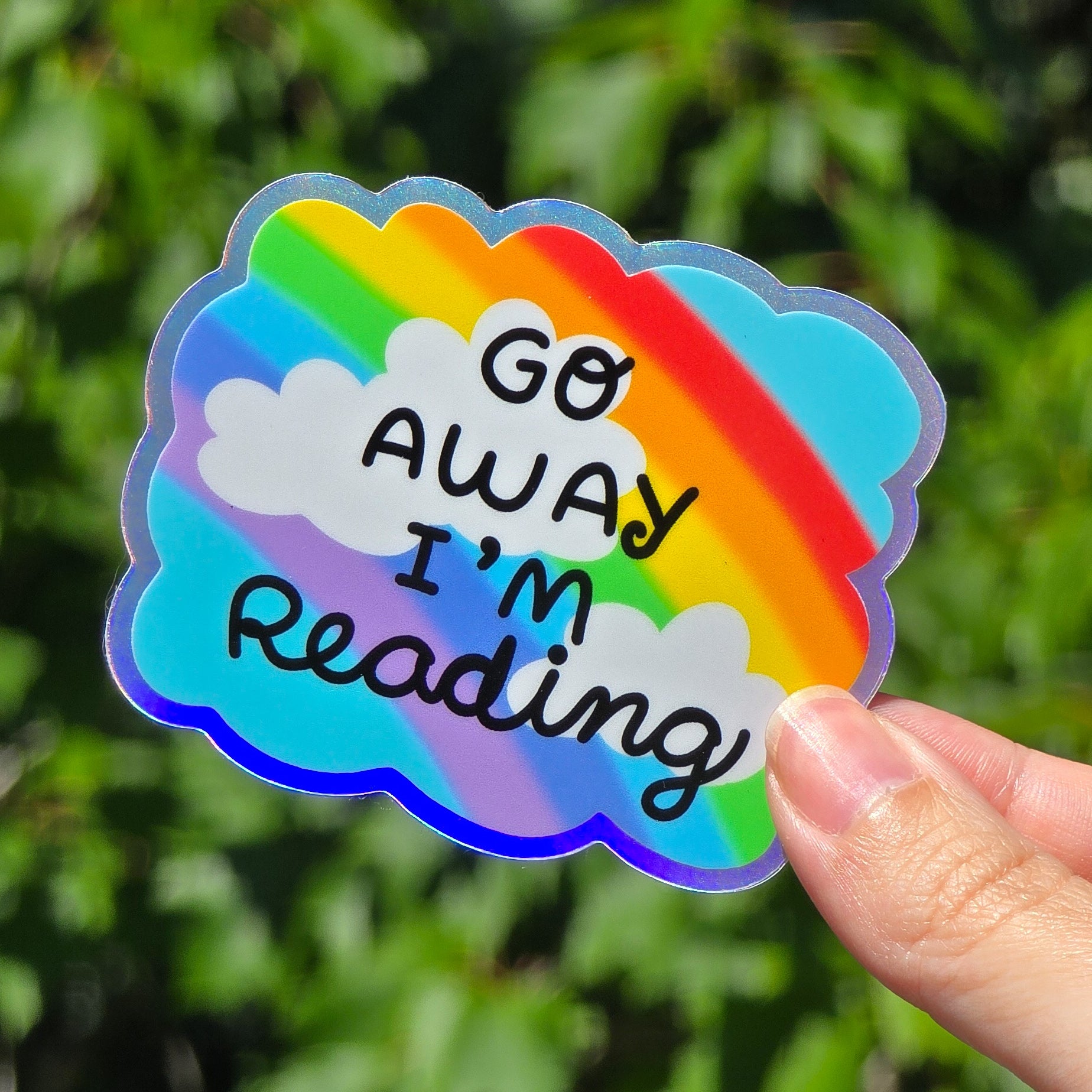 rainbow against a blue sky with clouds. it says go away i'm reading in black font. holographic border all around