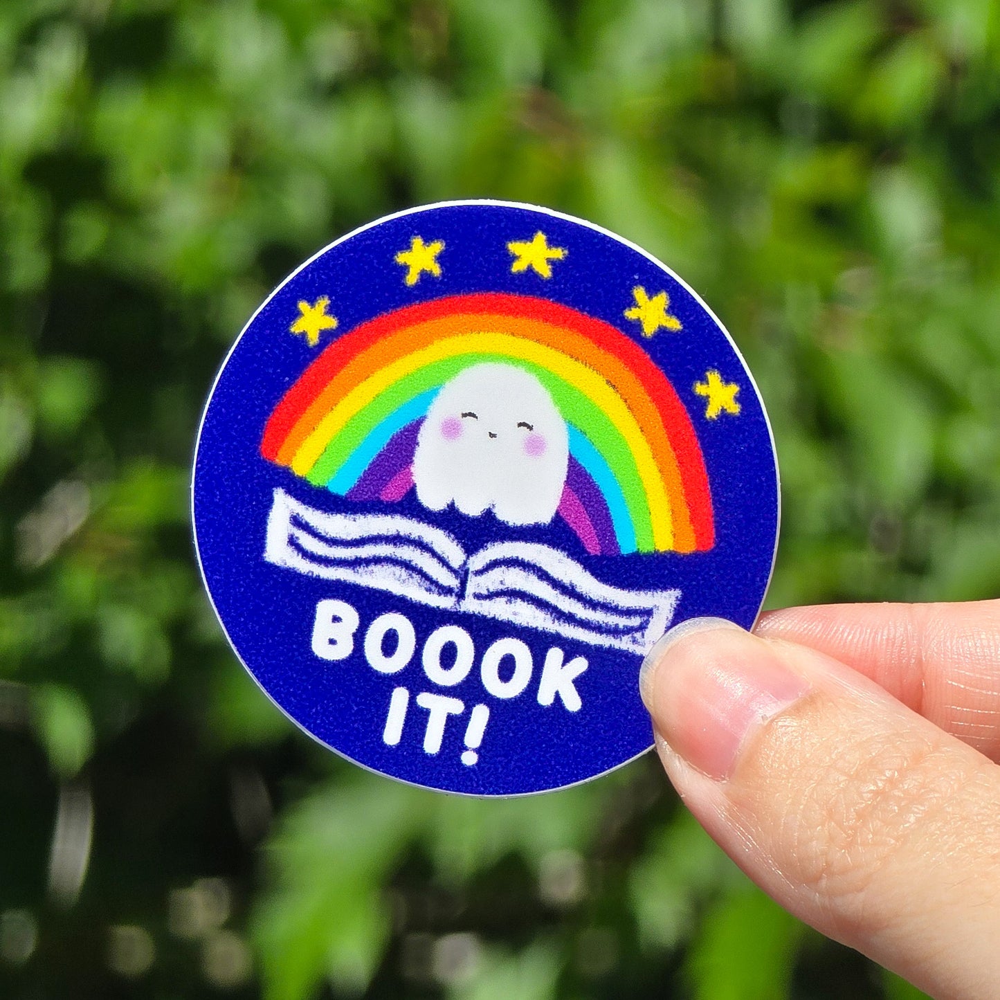 a circle sticker that says boook it featuring a ghost and rainbow made to look like the pizza reading club sticker