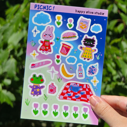 sticker sheet featuring picnic foods, a bunny, cat, and frog against a blue pink and green background. there are flowers and clouds and stars too