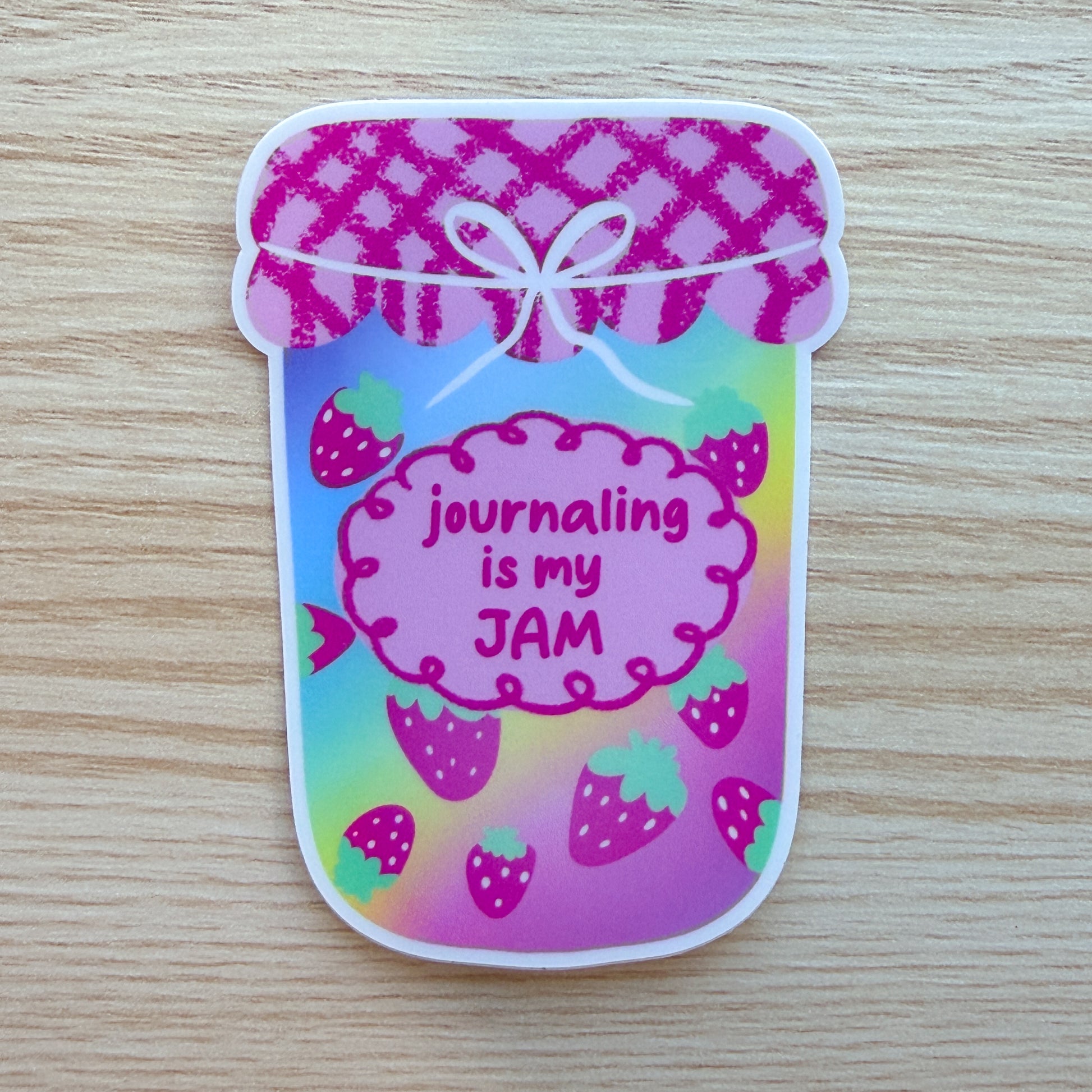 Colorful sticker with 'journaling is my JAM' text on a wooden surface