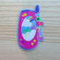 a pink early-2000s flip phone with a frog and cat on the front, and lucky-themed charms on the side
