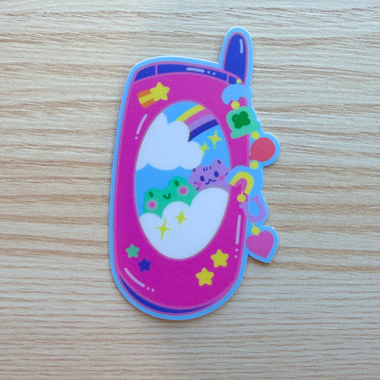 a pink early-2000s flip phone with a frog and cat on the front, and lucky-themed charms on the side