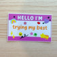 Colorful name tag sticker with 'Hello I'm trying my best' text on a wooden surface