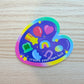 Colorful sticker with various symbols and 'create your own luck' text on a wooden surface