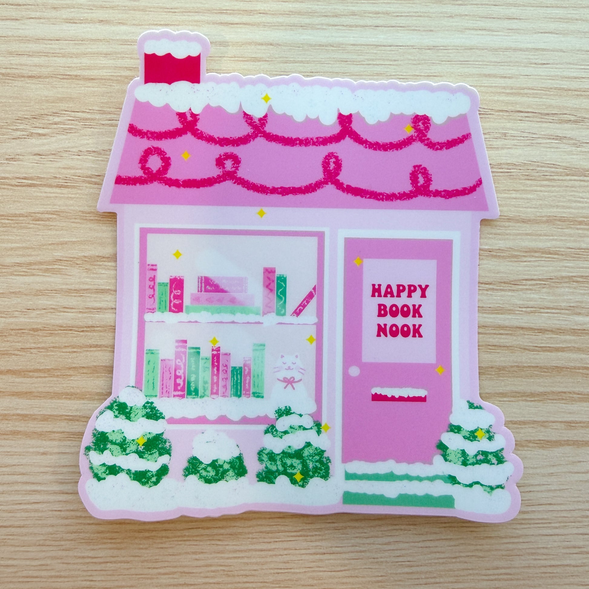Sticker of a pink bookshop with 'Happy Book Nook' on a wooden surface