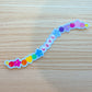 Colorful 'LOVE' sticker on a wooden surface in the shape of a long beaded bracelet