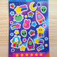 Colorful sticker sheet with various space themed designs on a wooden surface